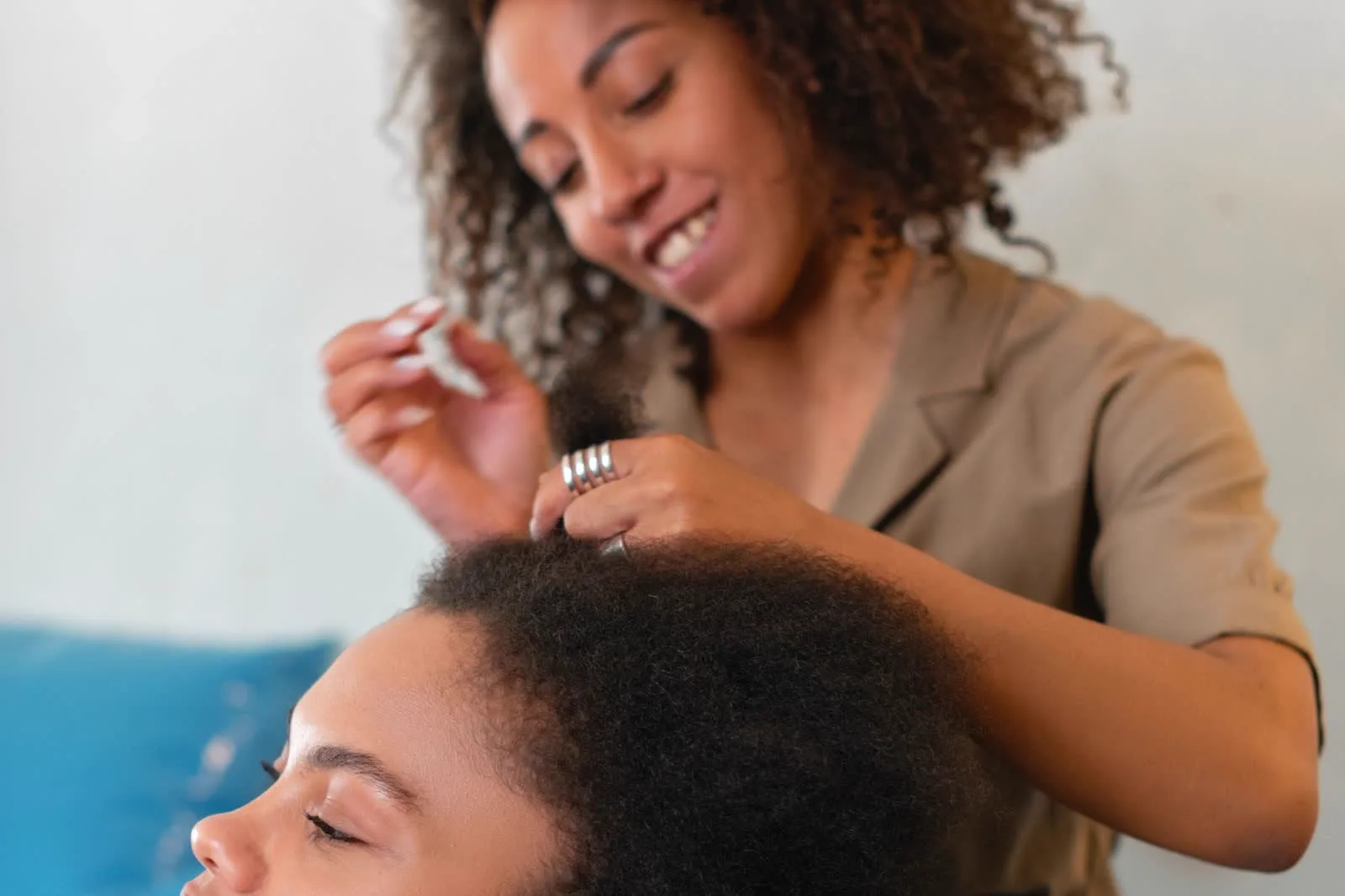 One woman gently applying hair product to another woman's coily type 4 hair