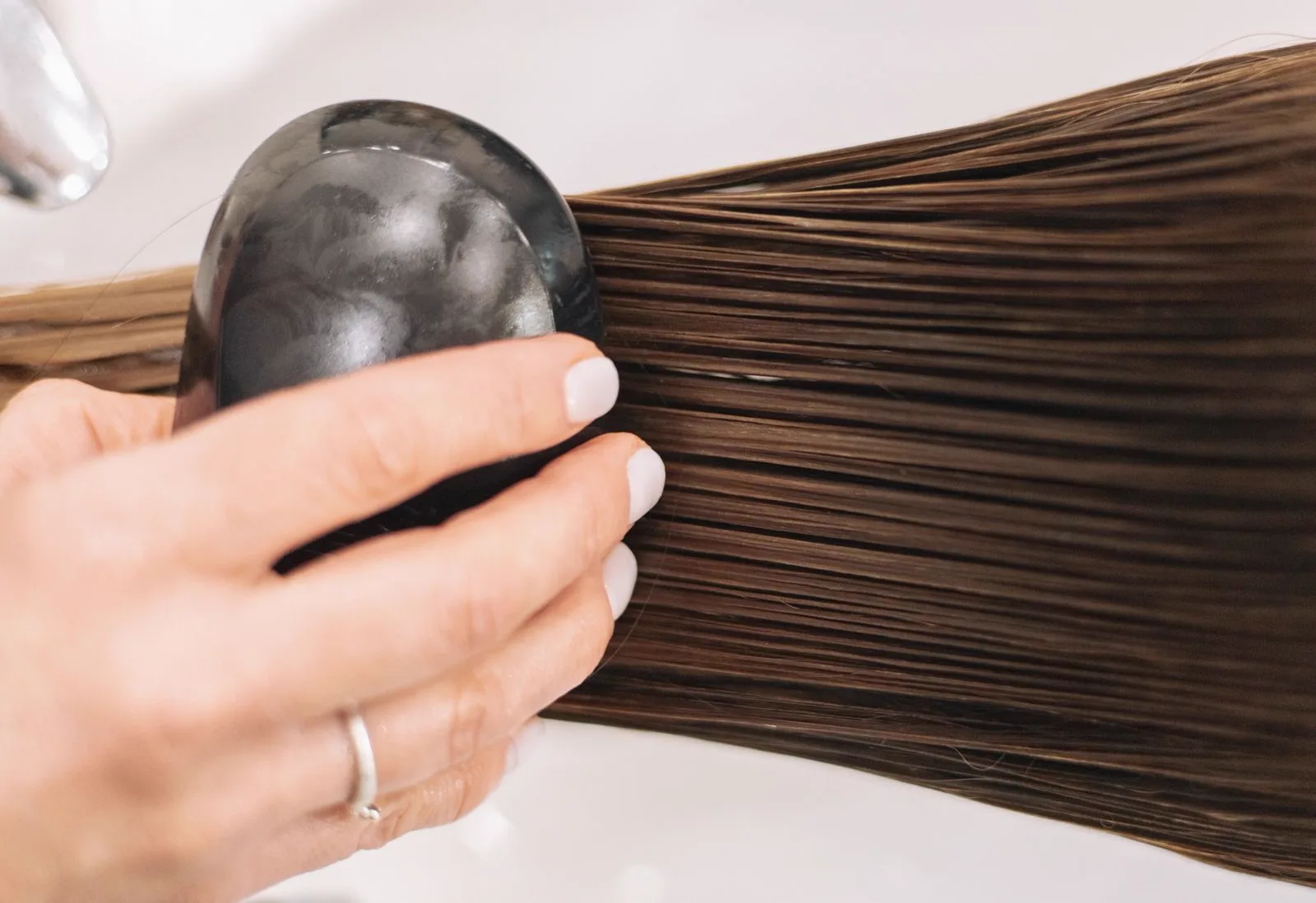A section of sleek, glossy straight hair being smoothed with a hair tool